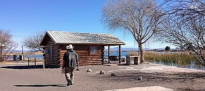 Man walking towards a cabin by the lake.