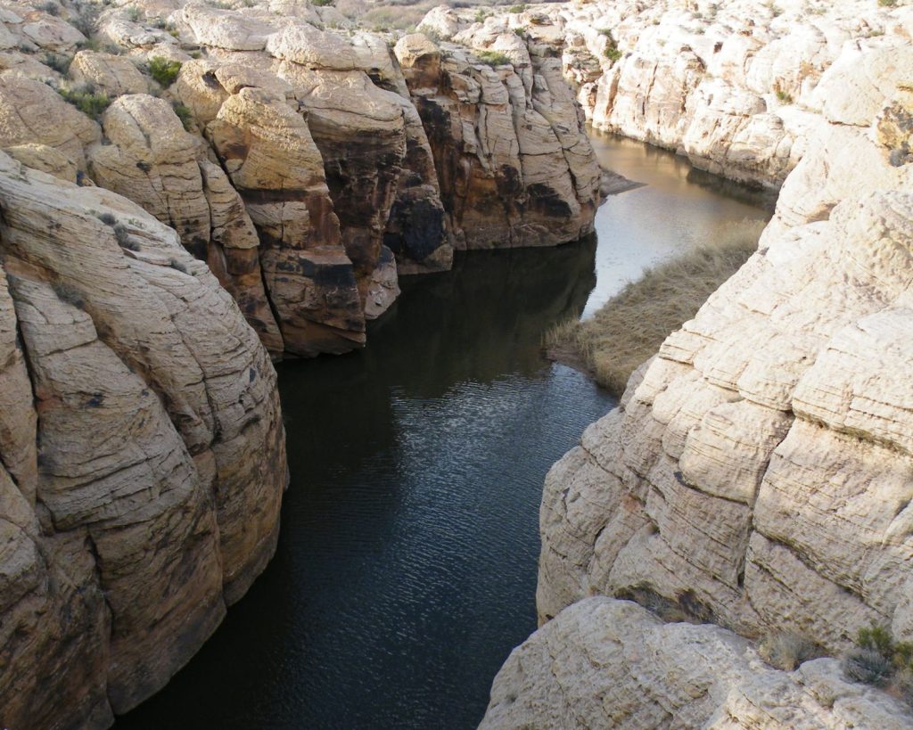 Creek flows through a canyon-like area of stark rocks and boulders. 