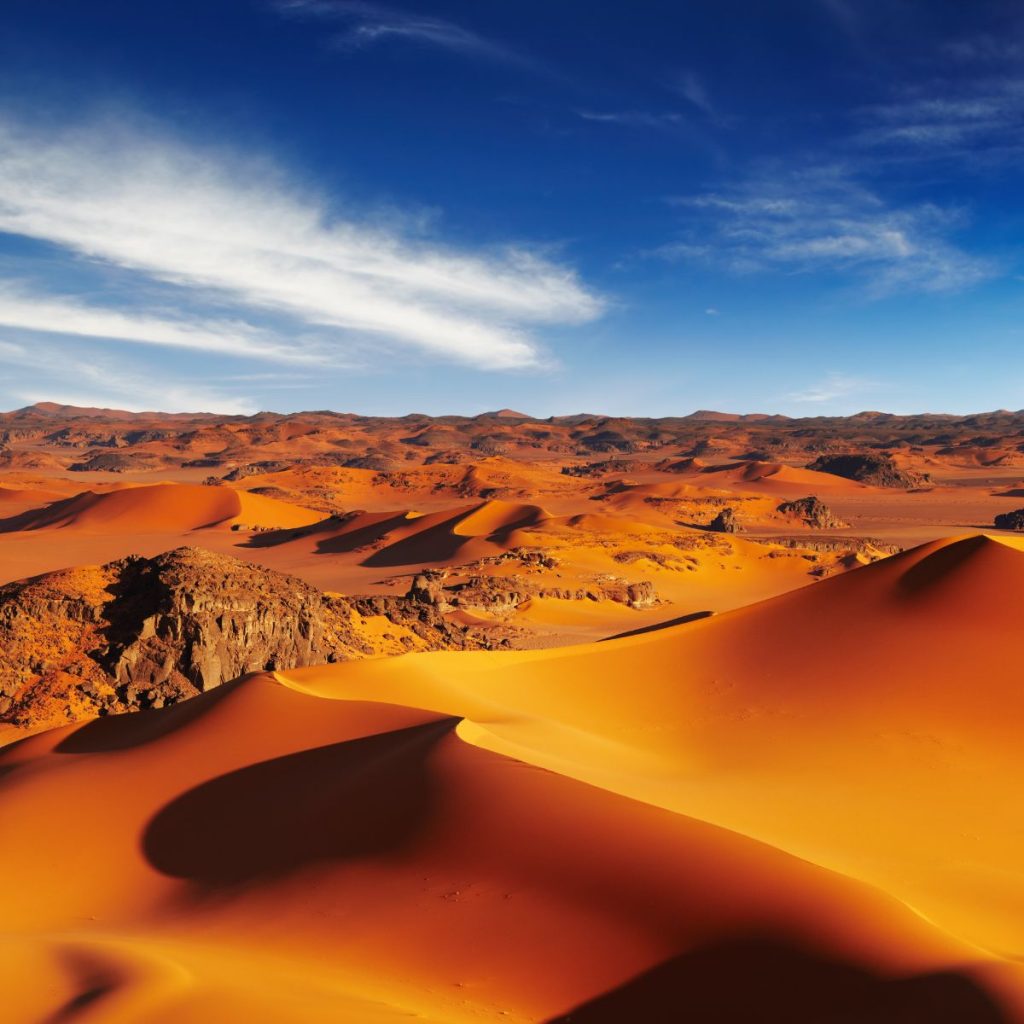 Sand Dunes with some rocky hills in a vast desert.